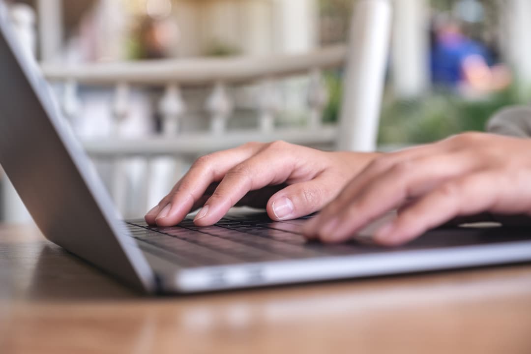 Hände tippen auf einem Laptop – Online-Formular ausfüllen